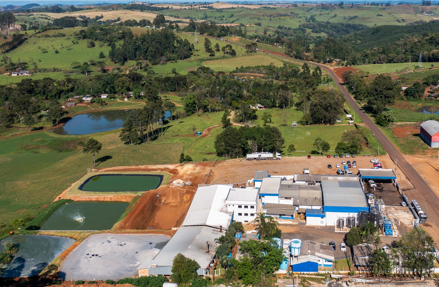 Vista aérea da fábrica e das lagoas de tratamento, cercadas por pastagens verdes.